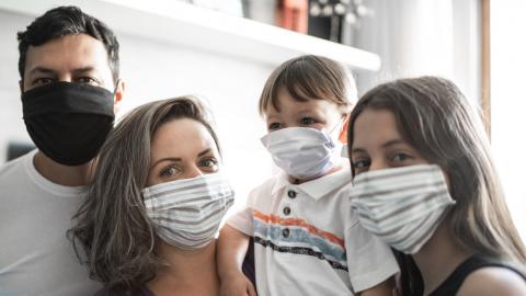 Una familia con tapabocas posan juntas en su hogar
