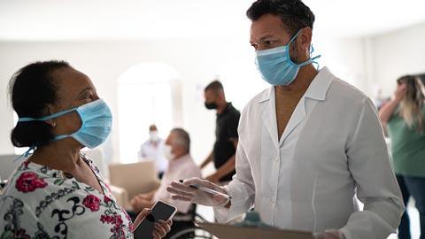 A woman and man wearing masks talk together in a community setting